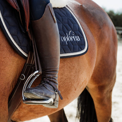 Rider on horse using the Ophena stirrups and Ophena saddle pad